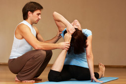 Photo of Male Professional Yoga Instructor guiding a client in a yoga pose.